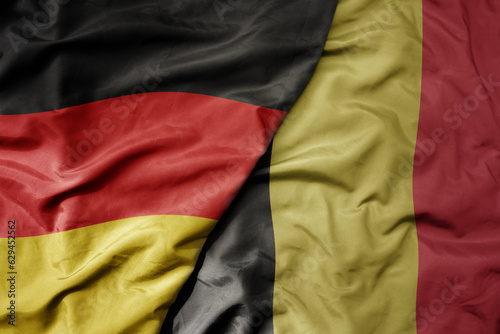 big waving realistic national colorful flag of germany and national flag of belgium .