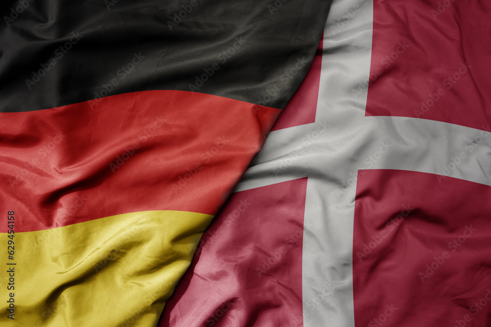 big waving realistic national colorful flag of germany and national flag of denmark .