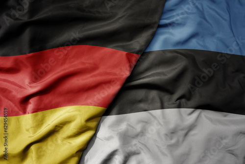 big waving realistic national colorful flag of germany and national flag of estonia .