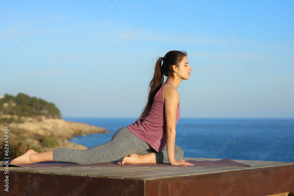 Woman doing yoga in a wooden terrace on the beach