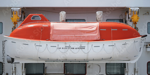 Orange lifeboat on the belly deck of a large ship photo