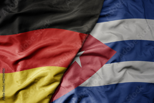 big waving realistic national colorful flag of germany and national flag of cuba .