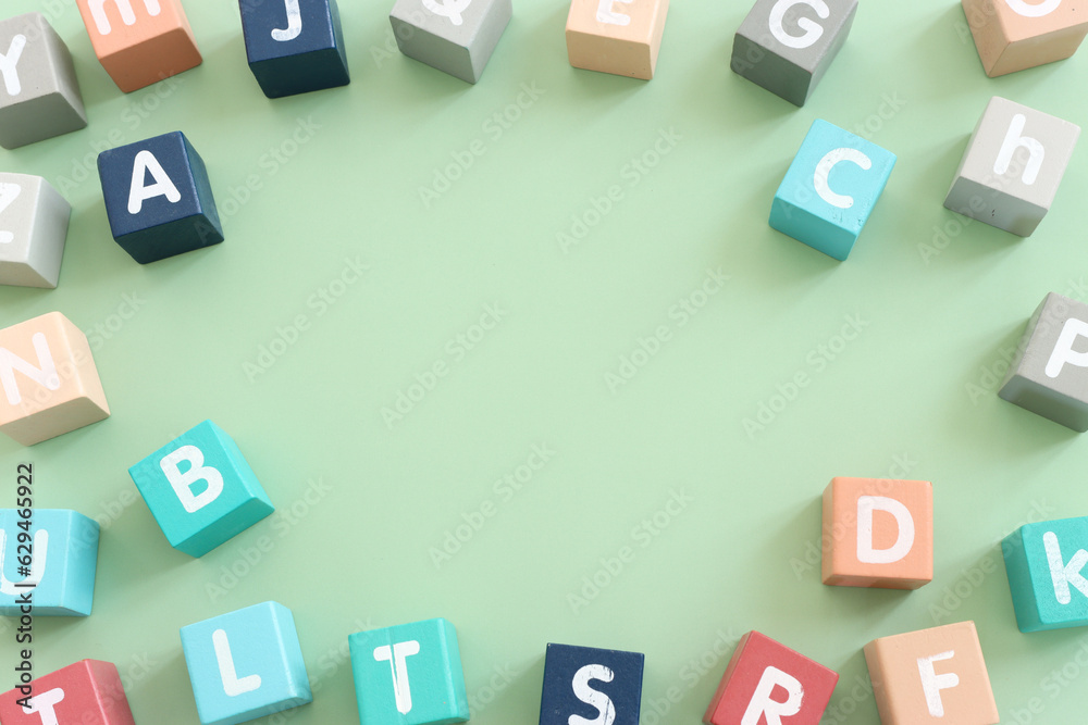 Wooden cubes with English letters on a pastel green background. ABC learning, education and language concept