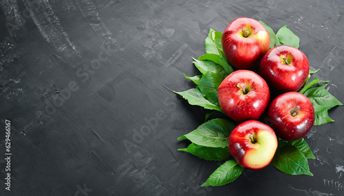 Fresh red apples with green leaves on a black background. Fruits. Top view. Free space for text.
