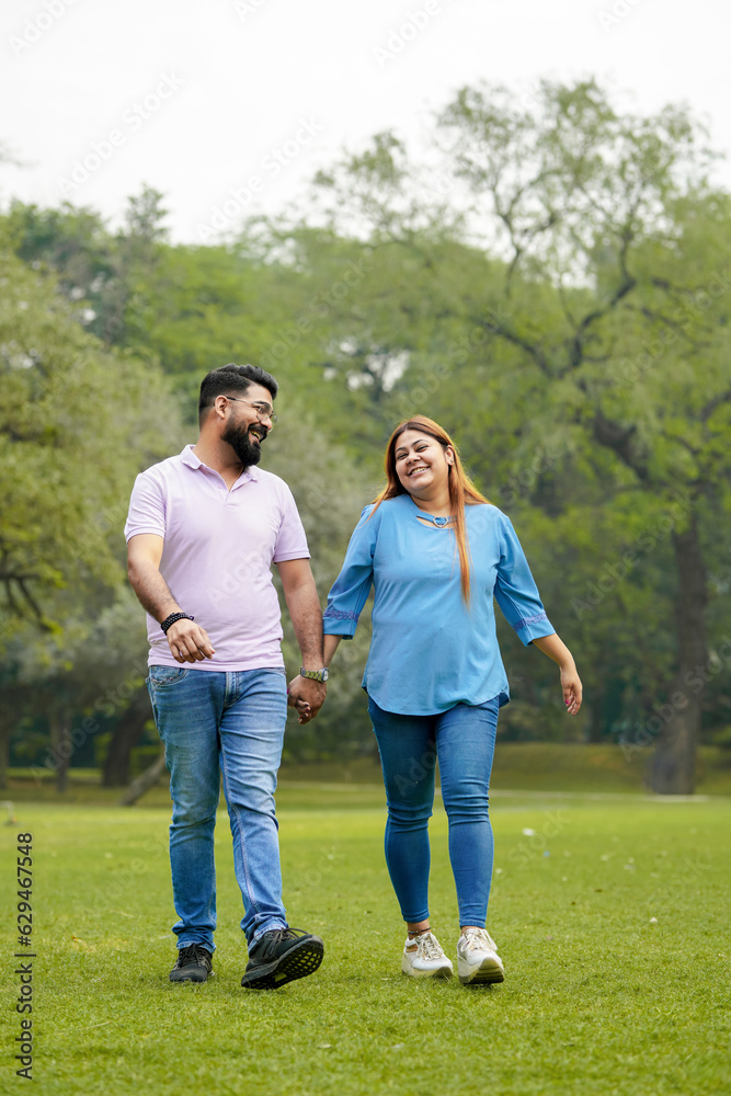 young indian couple holding hand each other and walking in park