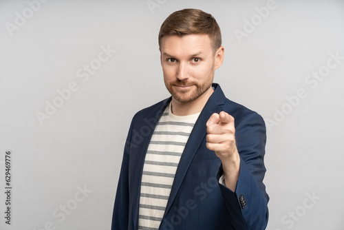 Confident recruiter pointing index finger ahead looking at camera smiling on grey background. Banner, poster for advertisement, marketing. Sincere human emotions. Headhunter man pointing at you.