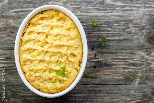 Potato mushroom casserole in baking dish on wooden background. Top view, copy space, flat lay. photo