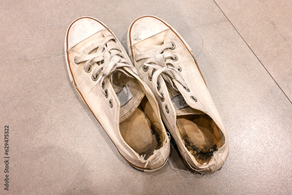 Naklejka premium Old and dirty white cream canvas sneakers.
