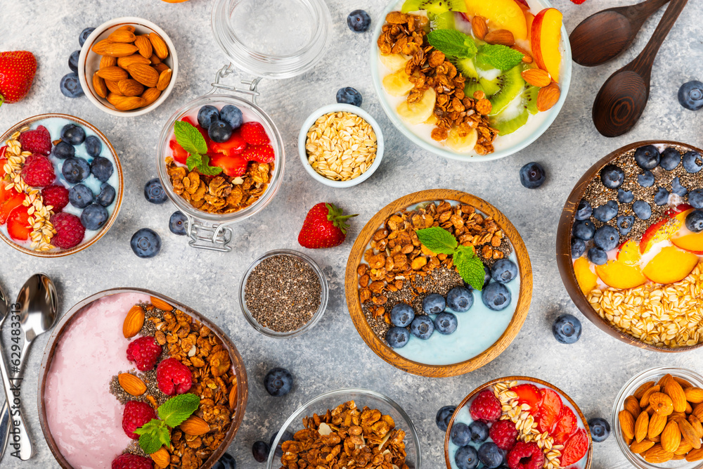 Bowl of granola with yogurt and fresh berries on a texture table. Yogurt berries, acai bowl, spirulina bowl. Healthy food, balanced breakfast. Strawberries, blueberries, kiwi, peach, almonds and chia.