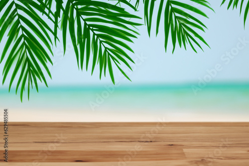 Summer beach party vibes with an empty wooden table and palm leaves against a blurred beach background. Perfect for summer time celebrations