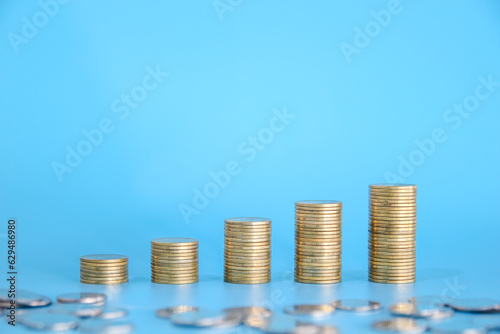 Stack of golden money coin on blue background with copy space. Business and finance background. 