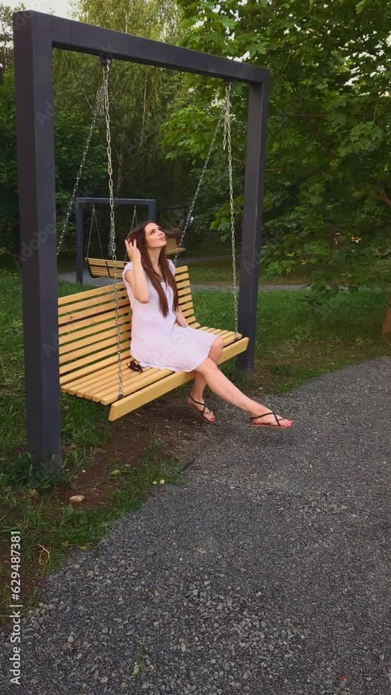Young woman carelessly swinging on swing in city park Young woman carelessly swinging on swing in city park