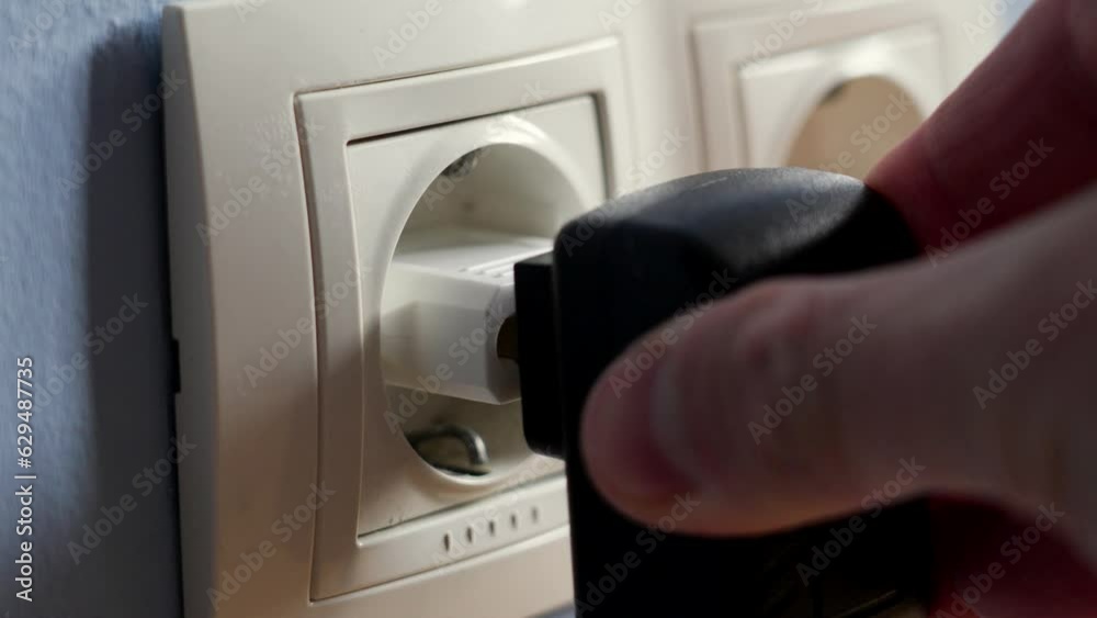 Connecting a mobile phone charger to a European electrical outlet through an adapter with a black power supply with an American plug type Connecting a mobile phone charger to a European electrical outlet through an adapter with a black power supply with an American plug type