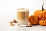 Autumn coffee latte in a transparent glass cup with cinnamon and pumpkins on a white background.