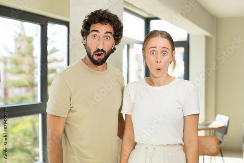 young adult couple looking very shocked or surprised, staring with open mouth saying wow
