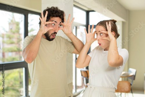 young adult couple keeping an eye on you, not trusting, watching and staying alert and vigilant