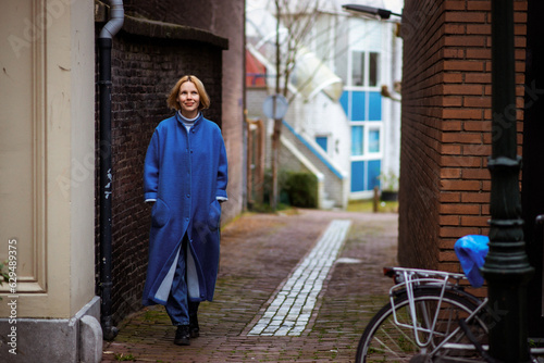 Weekend in the Netherlands, a woman in a blue coat walks along the road. Rest, travel in Europe.