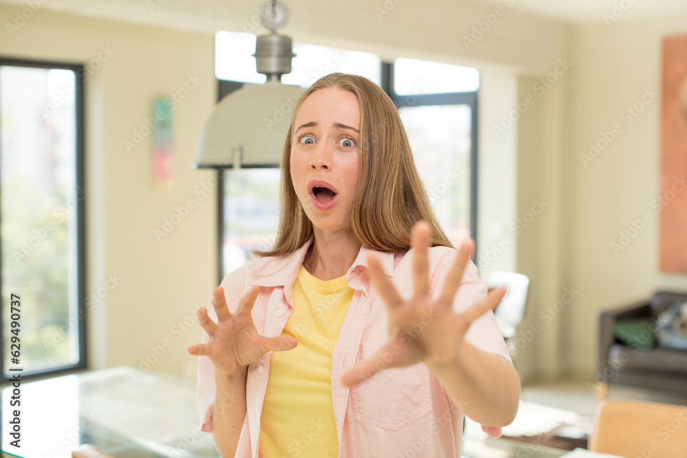 pretty blond woman feeling terrified, backing off and screaming in horror and panic, reacting to a nightmare