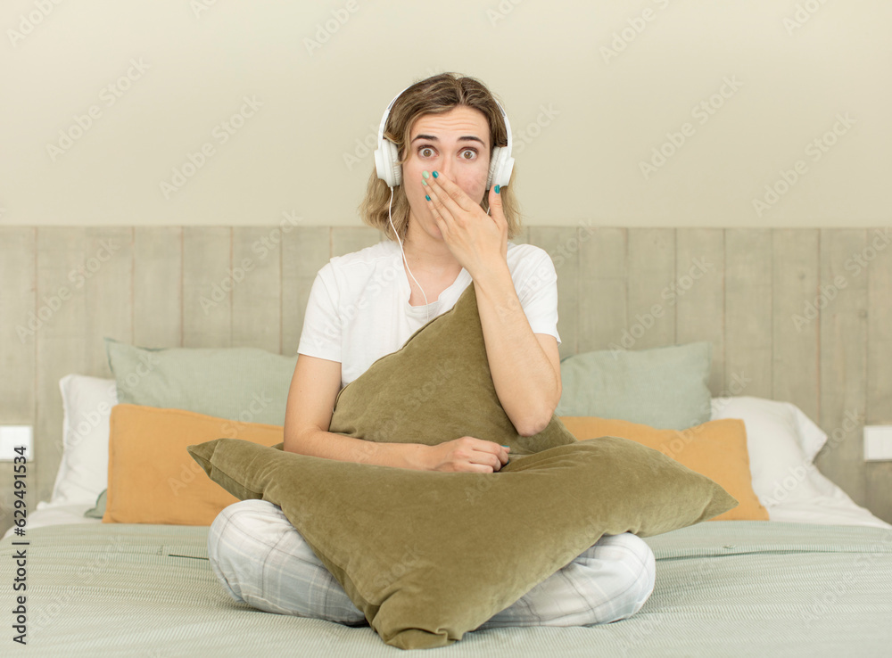 pretty woman covering mouth with a hand and shocked or surprised expression. nightwear and bedroom concept pretty woman covering mouth with a hand and shocked or surprised expression. nightwear and bedroom concept