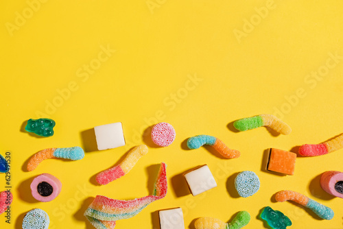 Assorted candies on bright yellow background