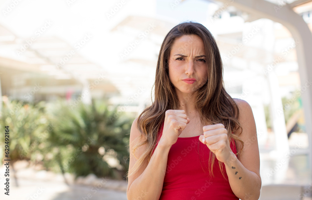 pretty woman looking confident, angry, strong and aggressive, with fists ready to fight in boxing position pretty woman looking confident, angry, strong and aggressive, with fists ready to fight in boxing position