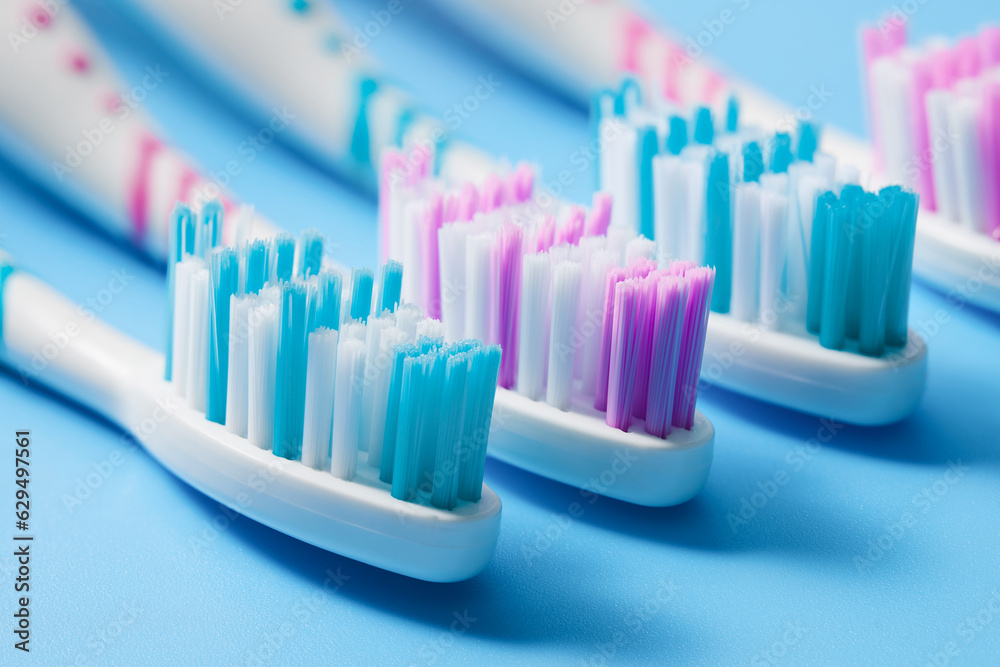 New unused manual toothbrushes of various colors on a blue background. Low angle view. New unused manual toothbrushes of various colors on a blue background. Low angle view.