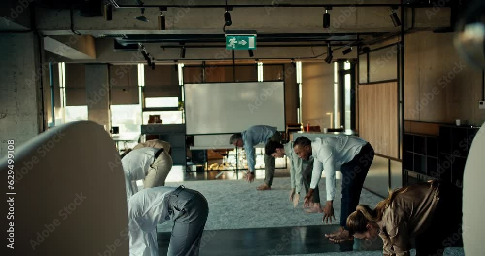 Overview of a group of business people in business attire doing yoga during a break at work in the office. Taking care of yourself, devoting time to your body and spirit at work