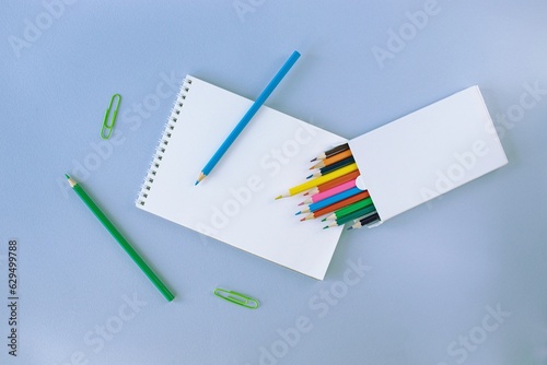 Back to school, colorful sticky notes and multicolored pencils, drawing supplies on gray blue background with copy space, top view, flatly