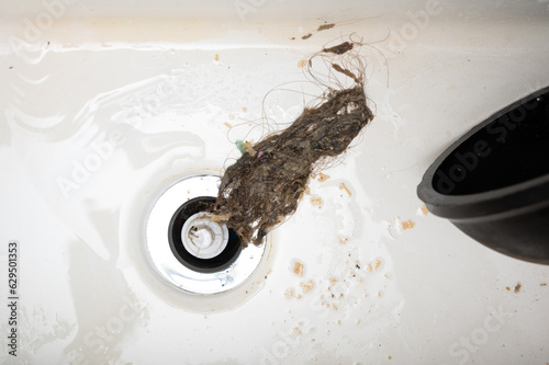 Removing blockage using drain cleaner. Old hair bunch caused sink drainage blockage