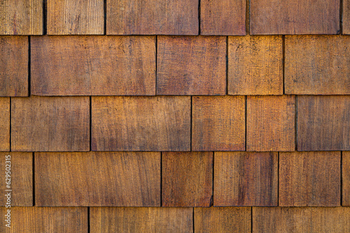 Close up of wood texture and background. Natural cedar shingle siding. Rough bumpy wood shingle cladding, row of wooden material of small shingle wall facade. Wood Shake Wall, Close Up texture
