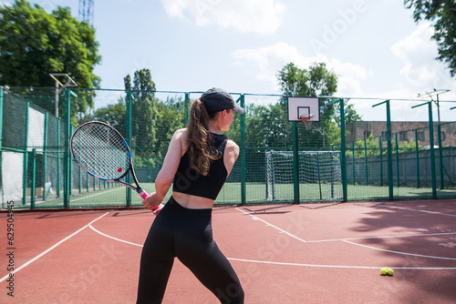 Sports girl with racket and tennis ball. A beautiful young girl is exercising. © Tania