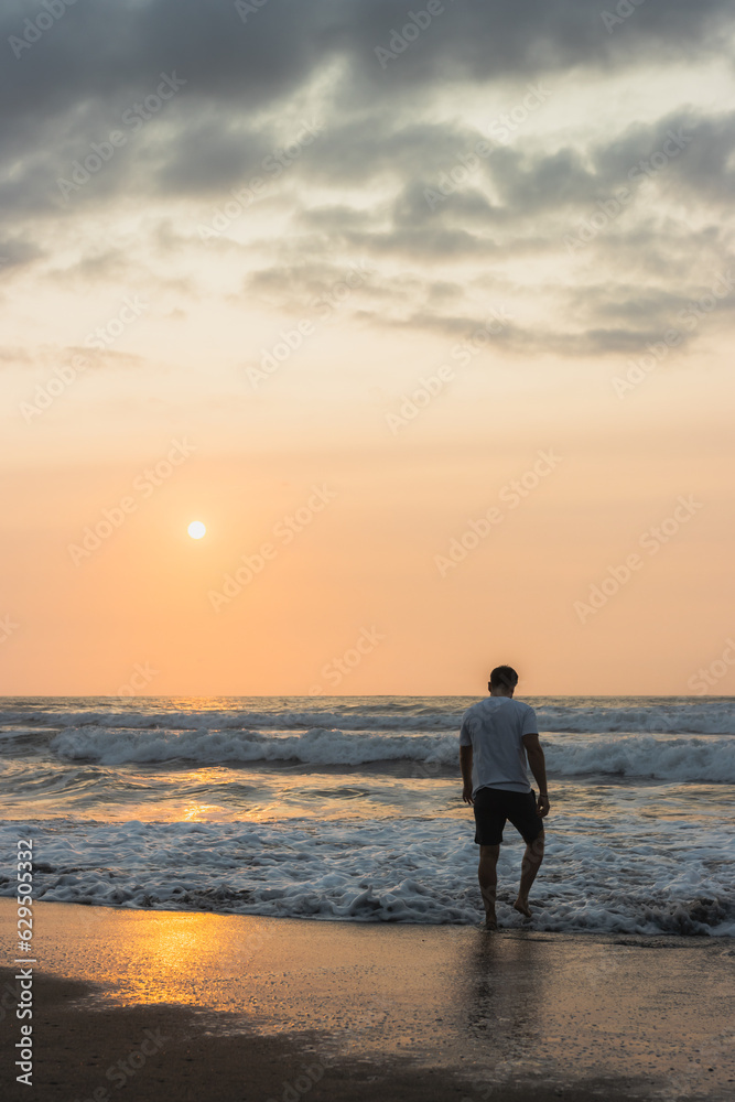 white man walking on the seashore at sunset
