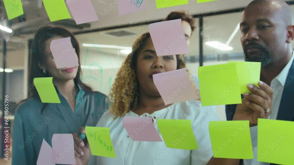 Group of multiracial business people talking while using sticky notes during meeting Group of multiracial business people talking while using sticky notes during meeting
