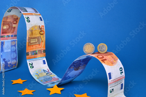 Close up of two Euros coins on a top of a background of Euros banknotes shaped like a roller coaster. photo