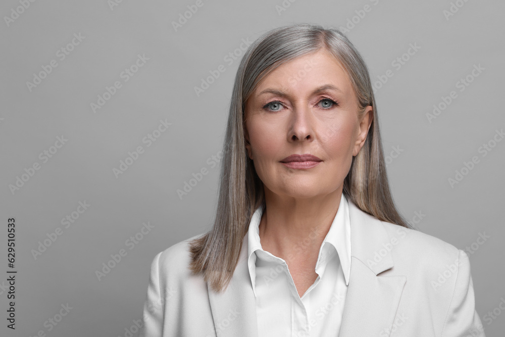 Portrait of beautiful senior woman on grey background. Space for text