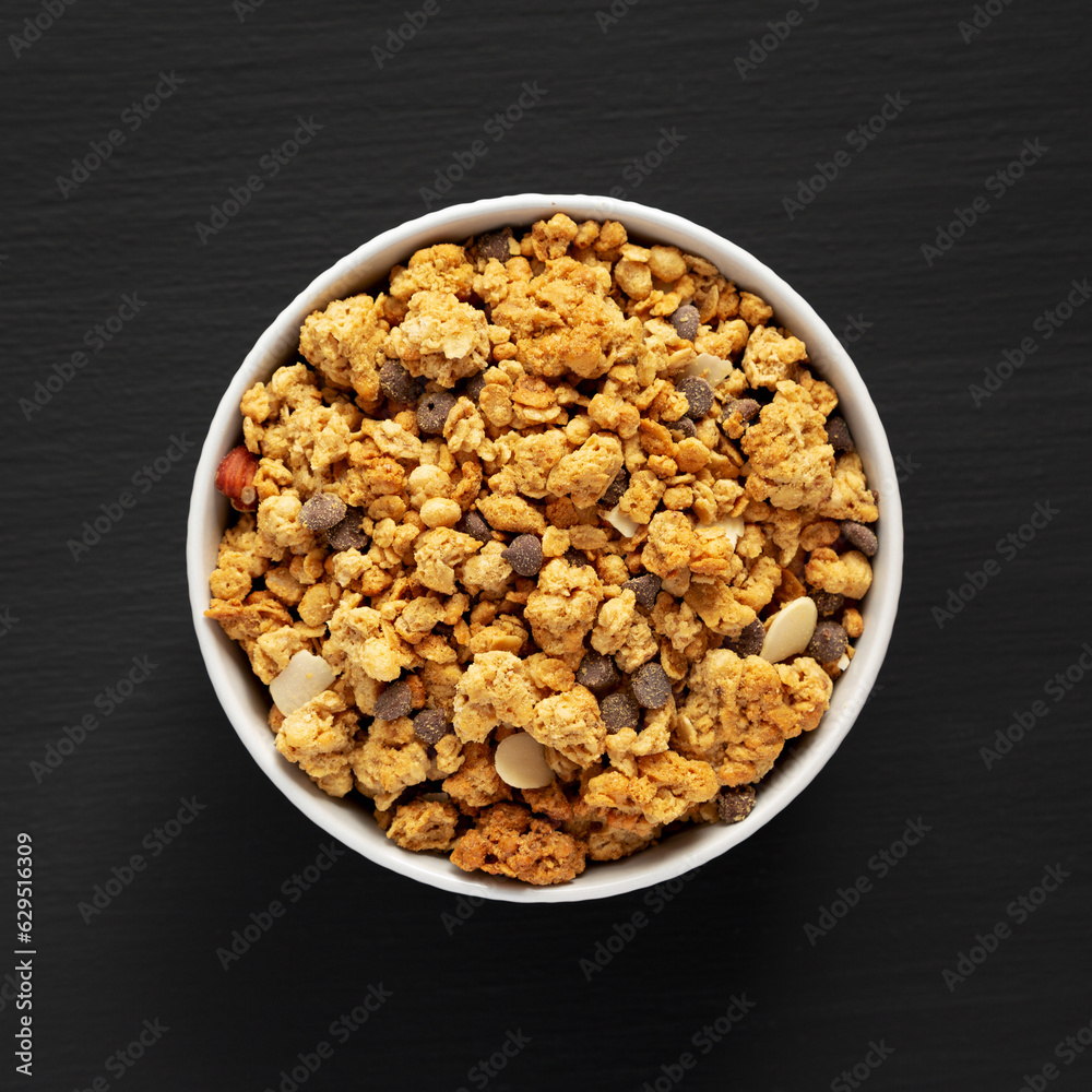 Protein Granola with hazelnut, almond, and chocolate in a Bowl, top view. Protein Granola with hazelnut, almond, and chocolate in a Bowl, top view.
