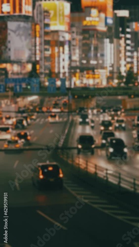 【縦型動画】夜の繁華街に自動車が通る都会の風景　東京の新宿　ぼかしあり