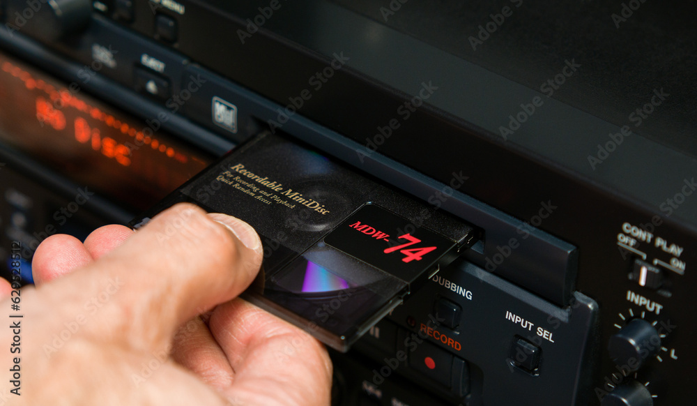 Man's hand removes a disc from the slot of a professional mini disc player