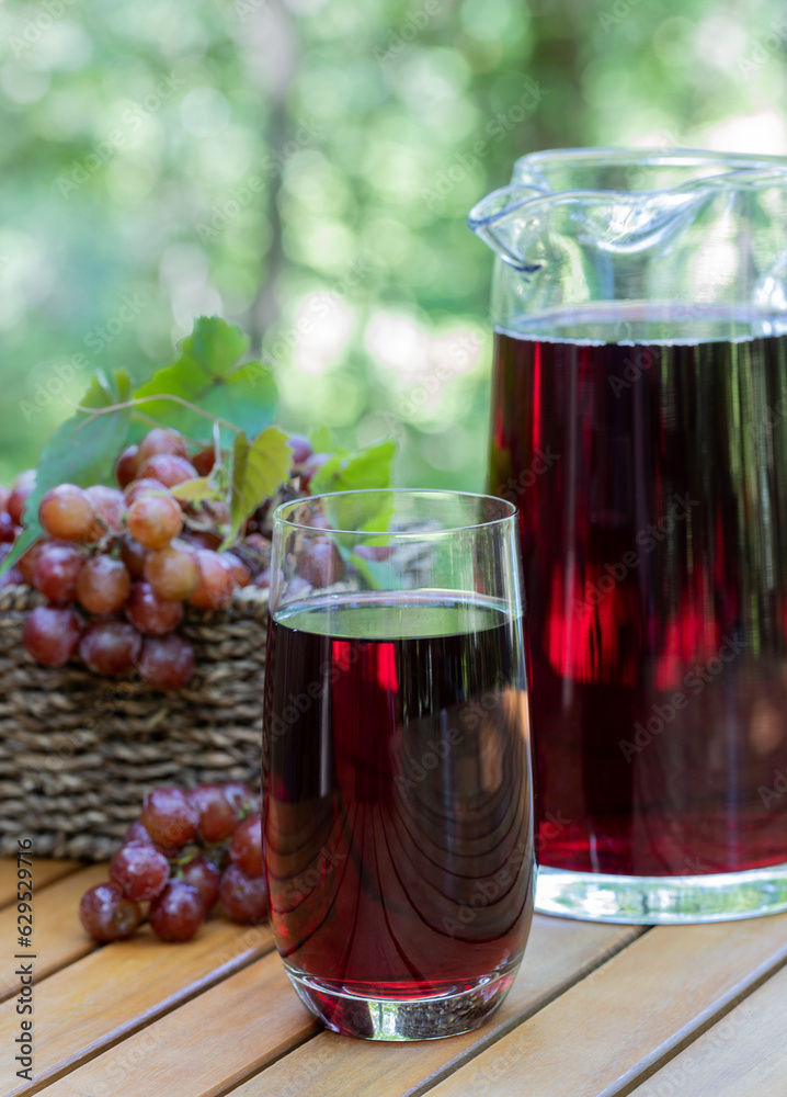 Grape juice in glass and pitcher with grapes in basket Grape juice in glass and pitcher with grapes in basket