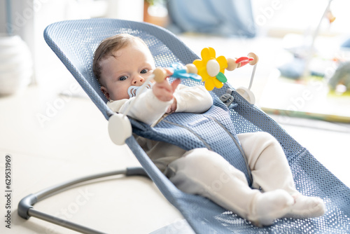 Photos Adorable 5 months old baby boy sitting in his swing rocking chair, playing with rotating toys