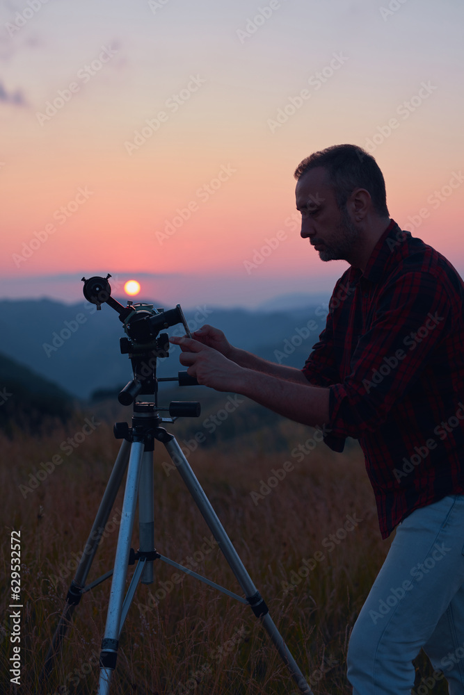 Astronomer looking at the sun with a telescope and using a cellphone.
