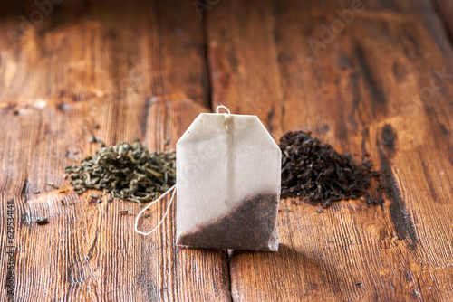 Tea bag, green and black tea on an old wooden table.