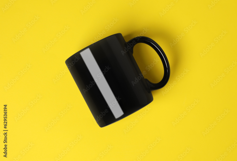 One black ceramic mug on yellow background, top view One black ceramic mug on yellow background, top view