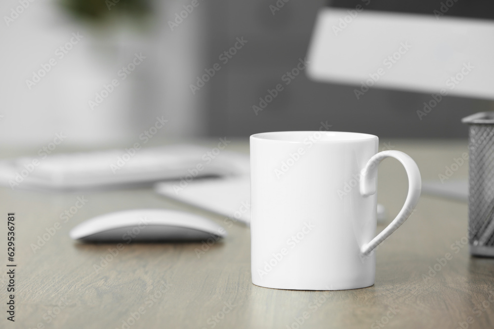 White ceramic mug on wooden table at workplace. Mockup for design White ceramic mug on wooden table at workplace. Mockup for design