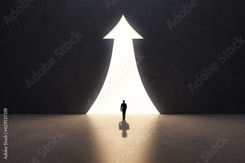 Back view of businessman silhouette in abstract concrete interior with upward arrow opening. Success, financial growth and future concept.