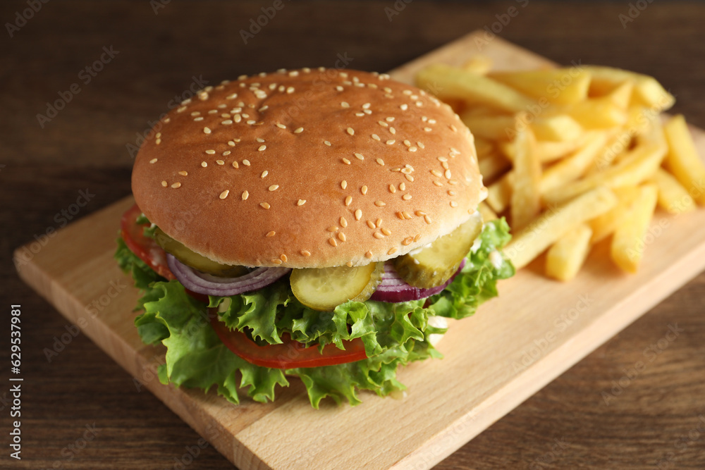 Delicious burger with beef patty and french fries on wooden table, closeup Delicious burger with beef patty and french fries on wooden table, closeup