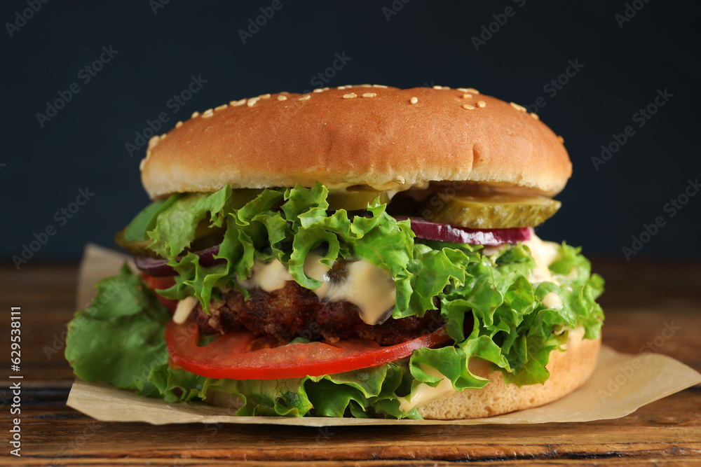 Delicious burger with beef patty and lettuce on wooden table, closeup