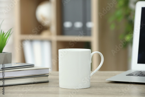 White ceramic mug and notebooks on wooden table indoors