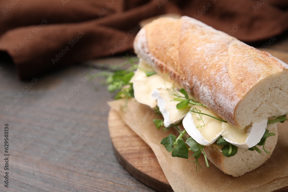 Obraz premium Tasty sandwich with brie cheese on wooden table, closeup. Space for text