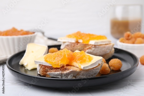 Tasty sandwiches with brie cheese, fresh raspberry and apricot jam on white table, closeup